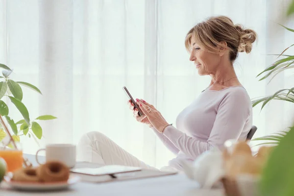 Mature Woman Having Breakfast Connecting Her Smartphone Home — Foto de Stock