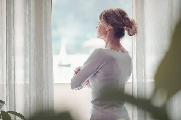 Mature Woman Relaxing Home Standing Next Window She Looking Away — Fotografia de Stock