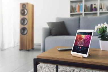 Podcast streaming on a tablet at home in the living room, technology and entertainment concept
