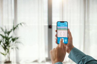 Woman locking a terrace door using her smartphone, smart home automation concept