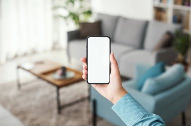 Woman connecting with her smartphone and using smart home apps, domotics and technology concept