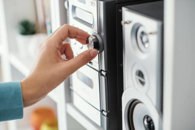 Woman adjusting a knob on the stereo system, home entertainment concept