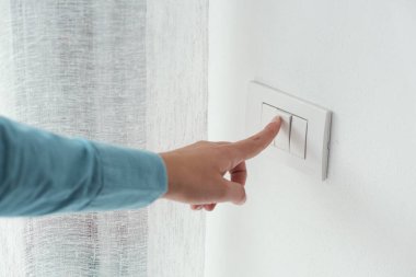 Woman pressing a light switch, energy saving concept