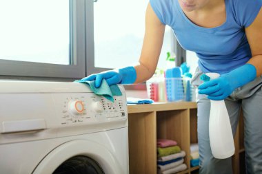 Woman holding a detergent and cleaning the washing machine, appliance hygiene concept