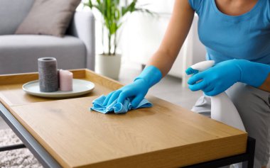 Woman cleaning a wooden table at home, hygiene and housekeeping concept, hands close up