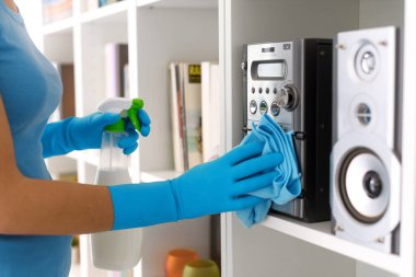Woman cleaning the stereo system at home, she is wiping with a cloth, hands close up
