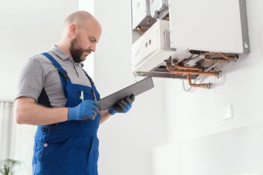 Gas engineer writing a gas safety certificate and boiler records after servicing