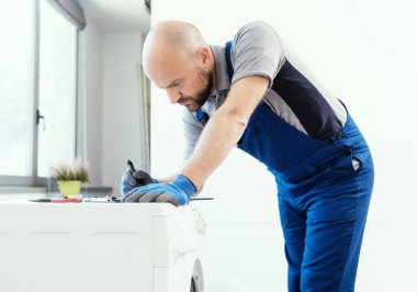 Professional technician writing an invoice after repairing a washing machine, home repair concept