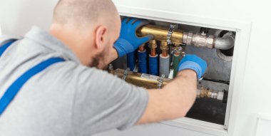 Professional plumber installing plumbing manifolds at home, home improvement and repair concept