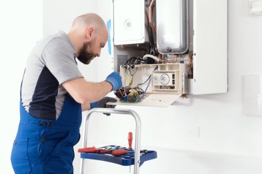 Professional qualified engineer servicing a natural gas boiler at home