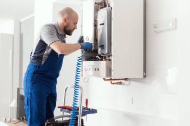 Gas engineer checking and cleaning a boiler during the inspection at home clipart