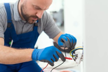 Professional electrician testing an outlet using a digital multimeter
