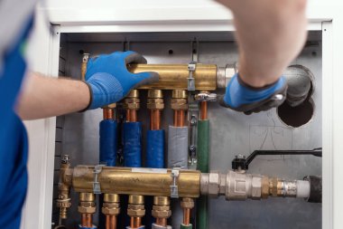 Professional plumber installing plumbing manifolds at home, home improvement and repair concept