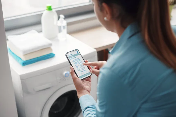 Woman Using Smart Washing Machine She Controlling Appliance Her Smartphone — ストック写真