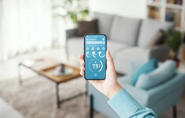 Woman setting the room temperature in her smart home: remote climate control on a smartphone