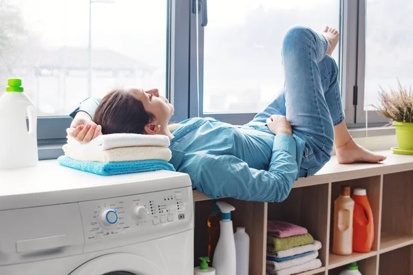 A housewife relaxes to the quiet hum of a running washing machine. Concept of quietness of new generation appliances.