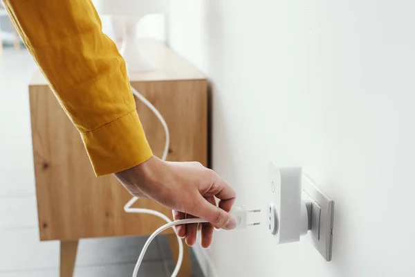 Woman plugging a device into a smart plug, virtual assistant and domotics concept