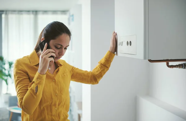 Worried Woman Calling Boiler Breakdown Emergency Service Using Her Smartphone — Zdjęcie stockowe