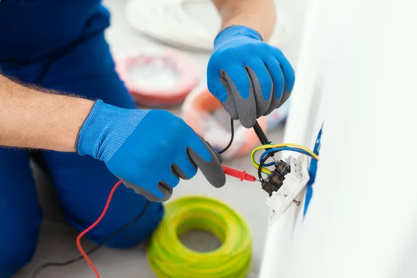 Professional electrician testing an outlet using a digital multimeter