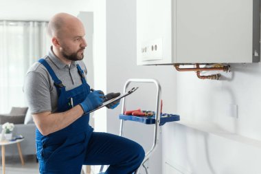 Gas engineer writing a gas safety certificate and boiler records after servicing
