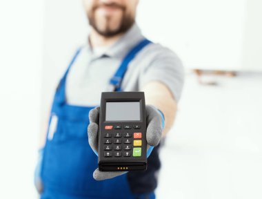 Professional repairman holding a POS terminal and waiting for the credit card, home repair and payments concept