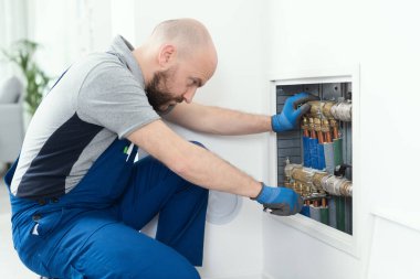 Professional plumber installing plumbing manifolds at home, home improvement and repair concept