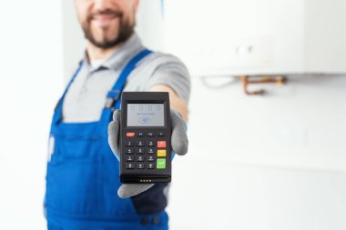 Professional repairman holding a POS terminal and waiting for the credit card, home repair and payments concept