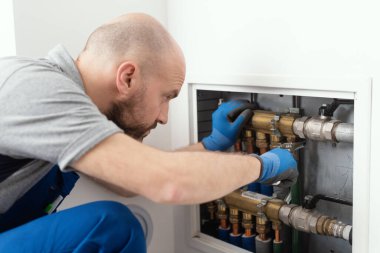 Professional plumber installing plumbing manifolds at home, home improvement and repair concept