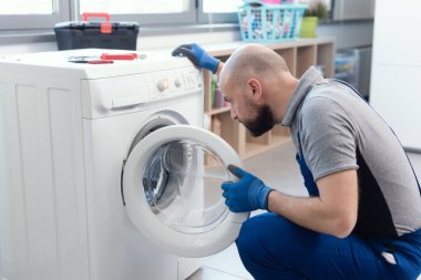 Professional technician checking a washing machine, he is adjusting a knob, home repair concept