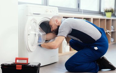 Professional technician repairing a washing machine, he is checking the gasket and door seal