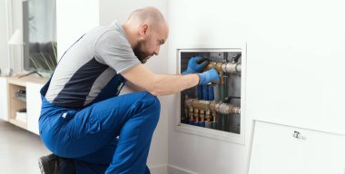 Professional plumber installing plumbing manifolds at home, home improvement and repair concept