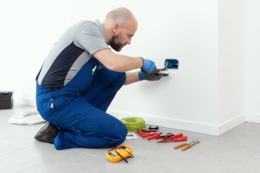 Professional electrician working on a home electrical system, he is installing a wall socket