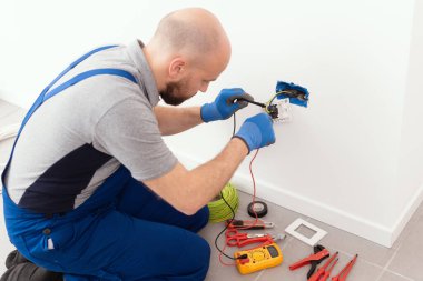 Professional electrician testing an outlet using a digital multimeter