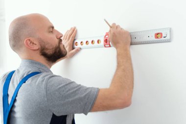 Professional handyman making measurement using a bubble level, home improvement concept