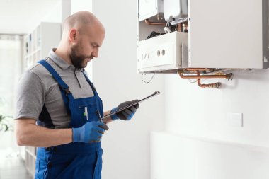 Gas engineer writing a gas safety certificate and boiler records after servicing