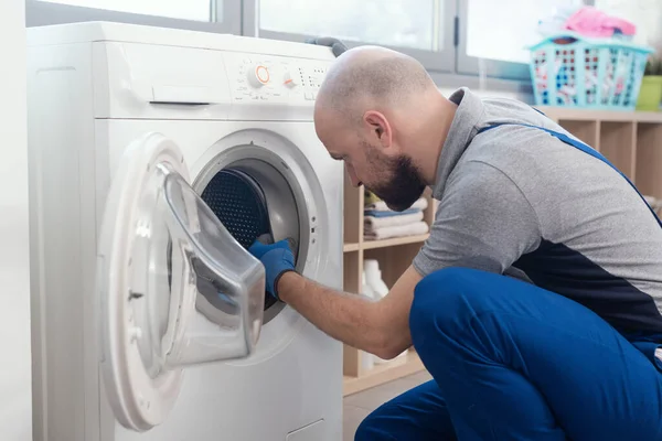 Professional technician repairing a washing machine, he is checking the gasket and door seal