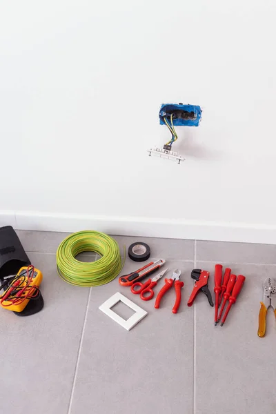 Wall socket installation at home: electrician tools on the floor