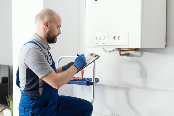 Gas engineer writing a gas safety certificate and boiler records after servicing
