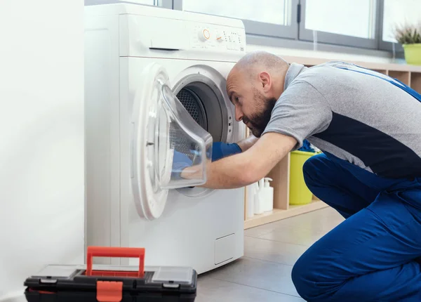 Professional technician repairing a washing machine, he is checking the gasket and door seal