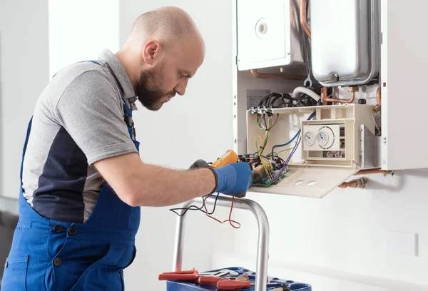 Professional boiler service: engineer checking the boiler printed circuit board using a digital multimeter