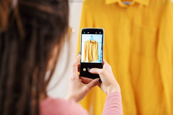 Woman taking picture of her used clothes, she is selling her clothing online