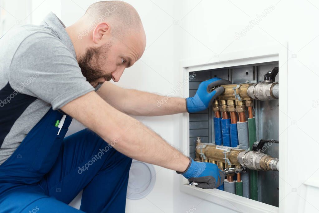 Professional plumber installing plumbing manifolds at home, home improvement and repair concept