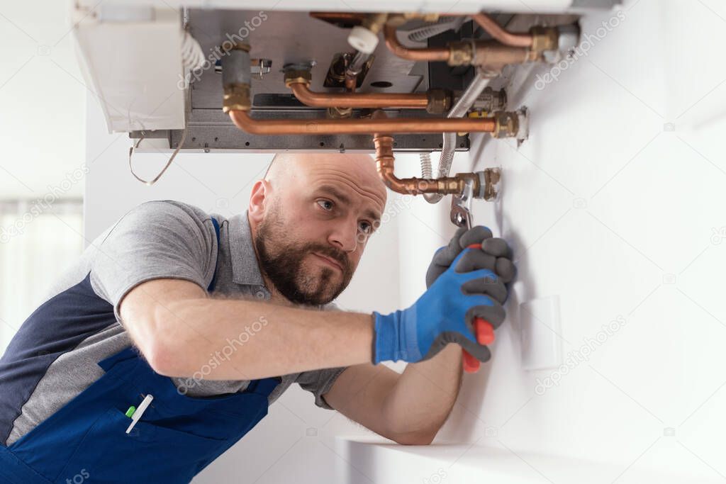 Professional engineer installing a natural gas boiler at home, he is checking the pipes