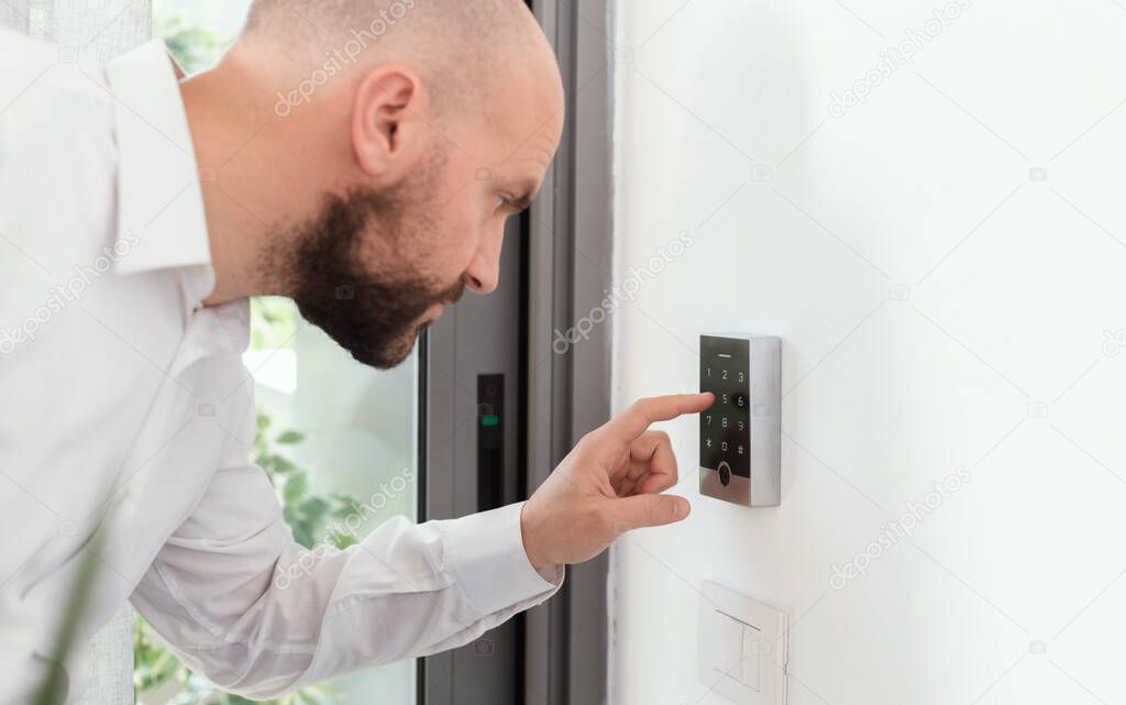Man setting an alarm code for home security, alarm system concept