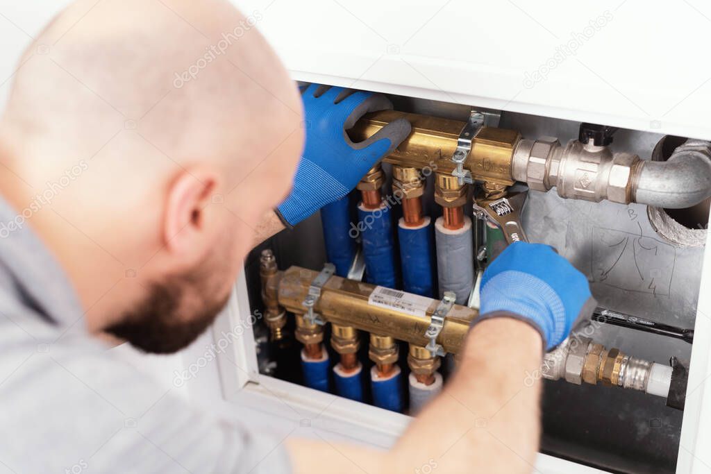 Professional plumber installing plumbing manifolds at home, home improvement and repair concept