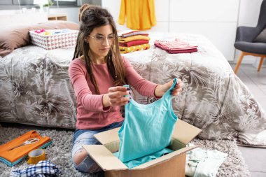 Young woman choosing clothes in her bedroom and organizing her wardrobe