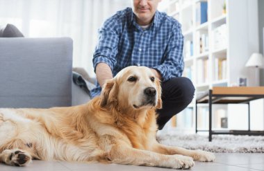 Man relaxing at home and cuddling his dog in the living room