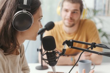 Young man and woman wearing headphones and doing a live podcast for their channel, communication and technology concept