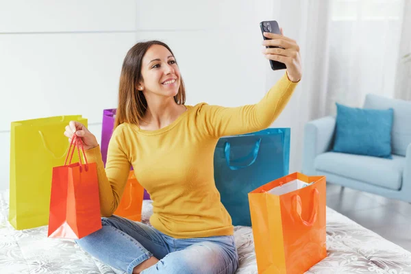 Happy Young Woman Sitting Bed Taking Selfies Her Shopping Bags — Stok fotoğraf