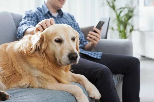 Man Sitting Couch Home Chatting His Smartphone Cuddling His Dog — Stockfoto